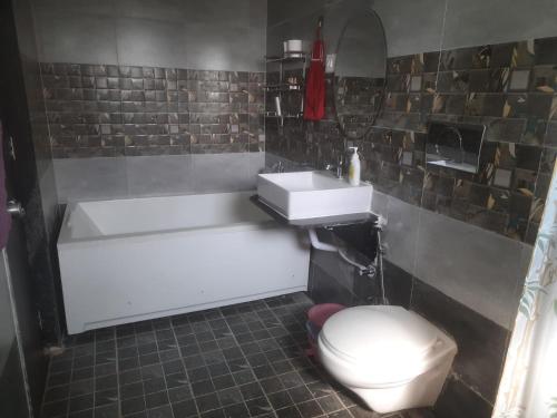 a bathroom with a tub and a toilet and a sink at Meghamala Bed and Breakfast in Kolthare