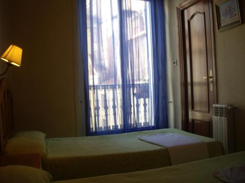 a bedroom with two beds and a large window at Hostal Pacios in Madrid