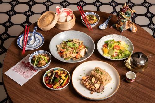 a wooden table with plates of food on it at GO INN Hua Lamphong - โกอินน์ หัวลำโพง in Samphanthawong