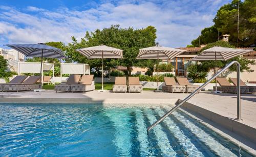 a swimming pool with umbrellas and chairs and a pool at Petit Garden Hotel by Flacalco in Cala Ratjada