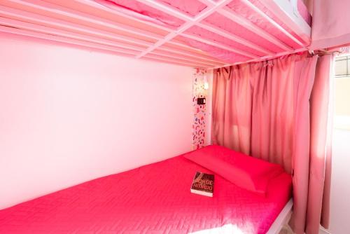 a bedroom with a pink bed with a book on it at Bela Curitiba Hostel in Curitiba