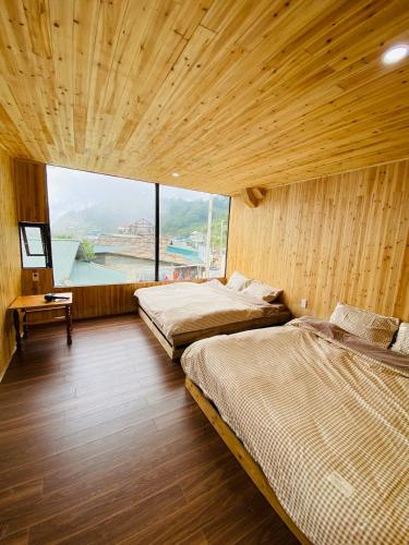 two beds in a room with a large window at A Phủ Home's Tà Xùa in Bắc Yên