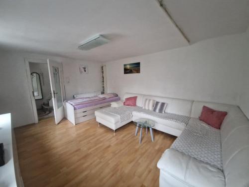a living room with white furniture and wooden floors at Ferienhaus an der Nieste in Niestetal