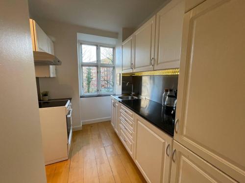 コペンハーゲンにあるComfy Valby Retreatの白いキャビネットと黒いカウンタートップを備えたキッチン