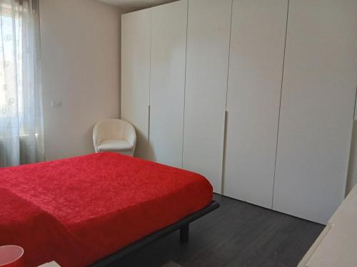 a bedroom with a red bed and a white cabinet at Appartamento Guido in Monfalcone