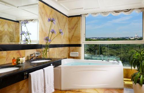a bathroom with two sinks and a tub with a large window at Parco dei Principi Grand Hotel & SPA in Rome