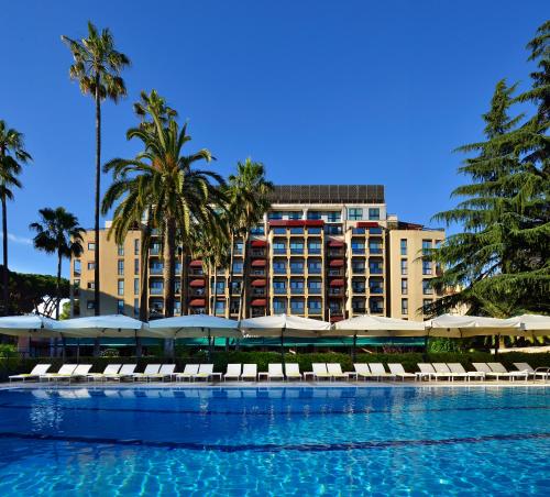 ein Pool mit Stühlen und ein Hotel im Hintergrund in der Unterkunft Parco dei Principi Grand Hotel & SPA in Rom