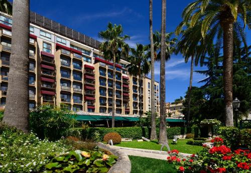 a building with palm trees and flowers in a park at Parco dei Principi Grand Hotel & SPA in Rome