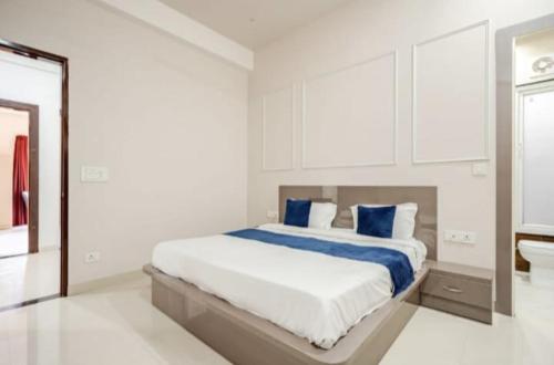 a white bedroom with a large bed with blue pillows at The Royal Harmony in Greater Noida