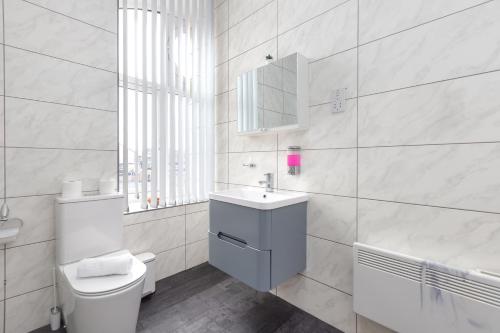 a white bathroom with a toilet and a sink at Charles Alexander Short Stay - South Pier Apartments in Blackpool