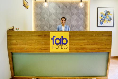 a man standing behind a counter with a tabo hotel sign at FabExpress Sumit Palace in Mumbai