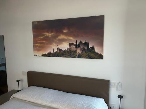 a painting of a castle on the wall above a bed at Nuovo B&B Colline San Benedetto in Marostica