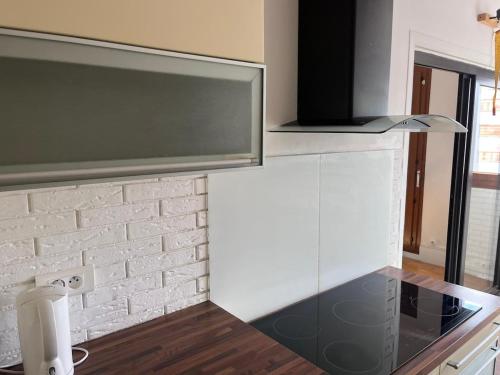 a kitchen with white cabinets and a brick wall at Appartement cozy et spacieux in Amiens