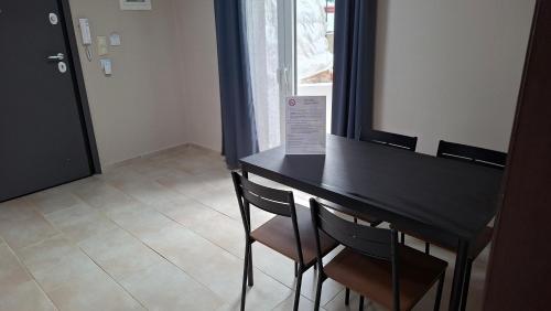 a black table and chairs in a room with a window at Akrata Green Elite Apartments in Akrata