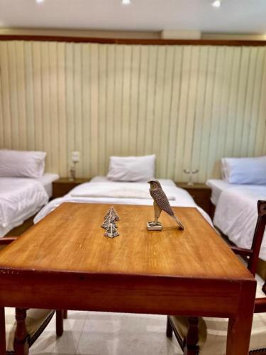 a bird statue sitting on a wooden table with two beds at Pyramids Grand View Hotel in Cairo