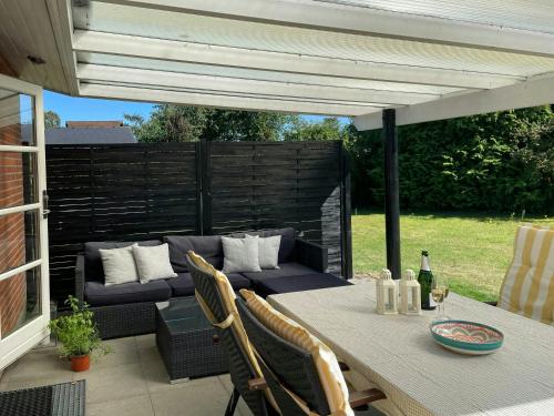 un patio con sofá, mesa y sillas en Modern Holiday Home With Spa At Grenaa Beach, en Grenå Strand