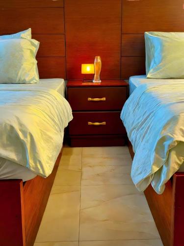a bedroom with two beds and a night stand with a lamp at Pyramids Grand View Hotel in Cairo