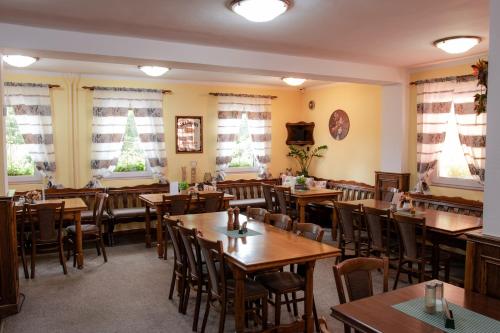 a restaurant with wooden tables and chairs and windows at Penzion & Restaurace Kozabar in Luby