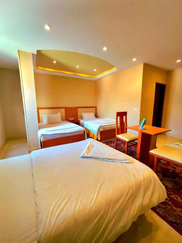 a hotel room with three beds and a table and chairs at Pyramids Grand View Hotel in Cairo