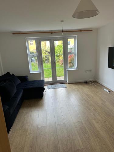 a living room with a black couch and some windows at Modern 3-Bedroom Home 3 Minutes from Biggin Hill Airport - Secure Gated Community in Biggin Hill