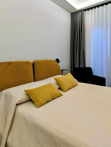 a bedroom with a bed with two yellow pillows on it at Porta di Castro Boutique Hotel & Pool in Palermo