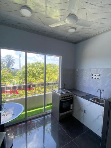 a kitchen with a stove and a large window at Naseema Hiya - Central Ukulhas Residences in Ukulhas