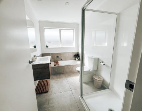 a white bathroom with a sink and a toilet at Modern Coastal Retreat in Pyes Pa in Tauranga
