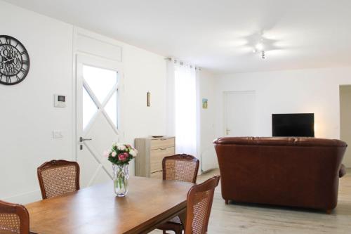 a dining room with a table and a couch at Renovated 2-bedroom apartment in Drancy