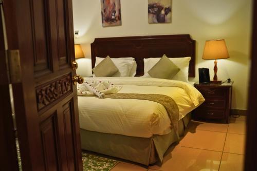 a bedroom with a large bed with white sheets and pillows at Sand Rose Hotel Apartments in Al Khobar