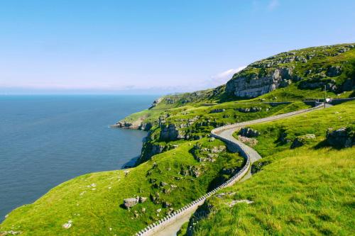 a winding road on a hill next to the ocean at The Promenâd in Llandudno