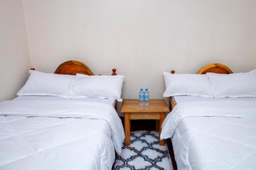 a room with two beds and a table with two bottles at Richard's Road Homestay in Boma la Ngombe