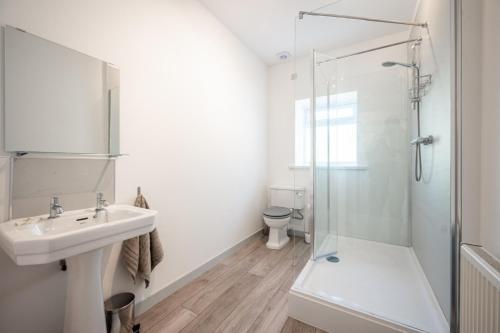 Un baño blanco con lavabo y ducha. en The Stables Cottage, Beattock, Moffat, en Beattock
