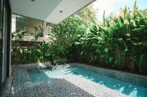 a swimming pool in front of a house with plants at Heart of Khao Yai Villa in Mu Si