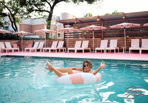 a woman is laying on an inner tube in a swimming pool at Walk to UT and E 6th in ATX House and Free Swim Club by Austin Vacay in Austin