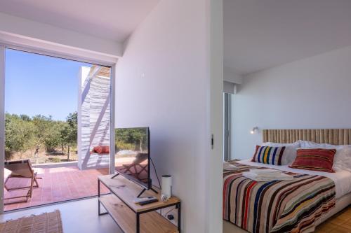a bedroom with a bed and a large glass window at Casa do Regadio in Zambujeira do Mar
