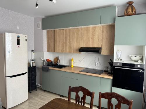 eine Küche mit weißem Kühlschrank und Holzschränken in der Unterkunft 3х комнатная квартира in Öskemen