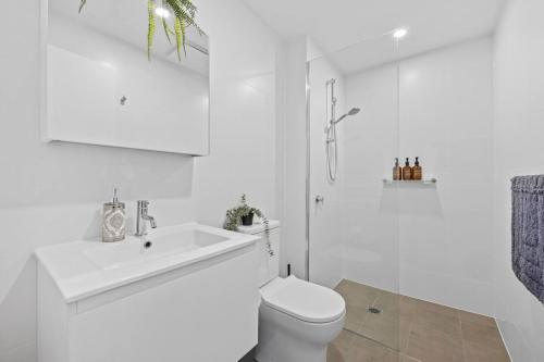 une salle de bains blanche avec toilettes et lavabo dans l'établissement Stylish Dickson 1BR Perfect for Business and Leisure, à Downer