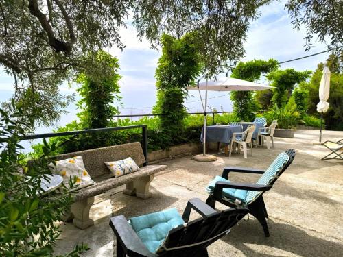 a patio with a bench and chairs and a table at Gli Orti sul mare 1 Vista mare in Bordighera