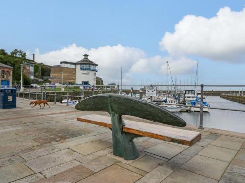 a bench in a marina with a dog running behind it at Duncan Square in Whitehaven