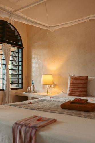 a bedroom with a bed with a lamp and a window at Banana House and Wellness Centre in Lamu