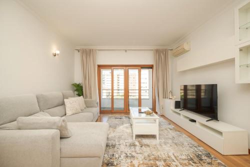 a living room with a white couch and a tv at Odivelas Premium By Hosty in Odivelas