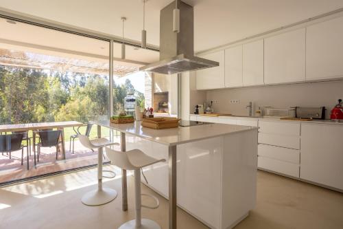 a kitchen with white cabinets and a table with chairs at Casa do Regadio in Zambujeira do Mar