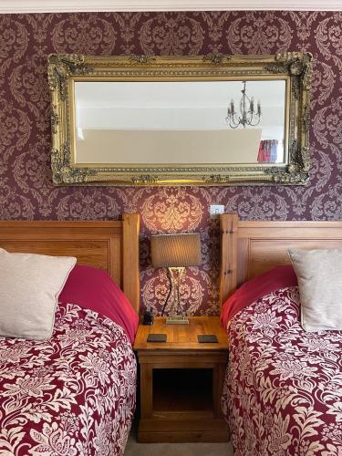 a bedroom with two beds and a mirror on the wall at Park View Apartment & Rooms in Scarborough