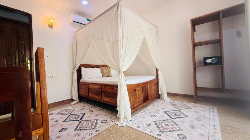 a bed with a canopy in a room at Moya Beach Hotel in Marumbi