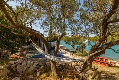 a hammock hanging from a tree next to a body of water at Villa Zora ZadarVillas - private island retreat in Sali