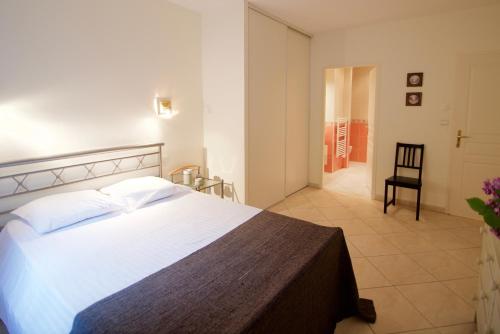 a bedroom with a large white bed and a chair at L'Arcadia Panoramique - Terrasse Vue Lac et Piscine in Talloires