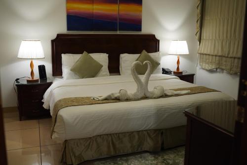 アル・コバールにあるوردة الرمال للأجنحة الفندقيةの2羽の白鳥の像が置かれたベッドのある寝室