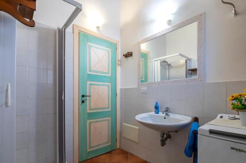 a bathroom with a sink and a mirror and a door at Rifugio Del Sognatore Stintino in Cuile Pazzoni