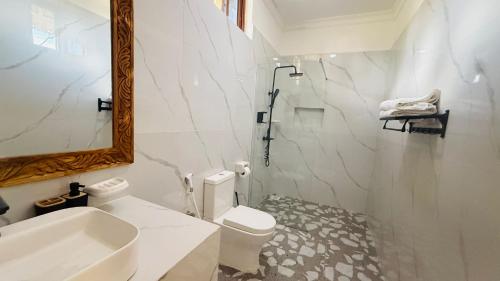 a bathroom with a sink and a toilet and a mirror at Moya Beach Hotel in Marumbi