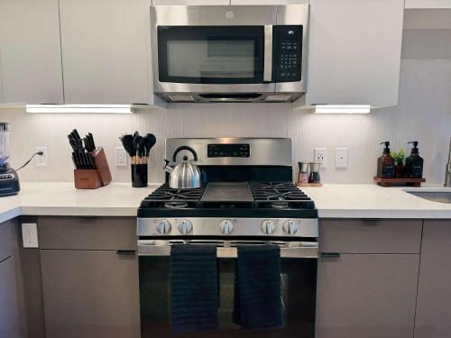 a kitchen with a stove and a microwave at Sunlit Retreat 10 Min from Disneyland With Pool & GYM in Tustin